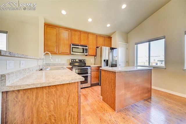 kitchen with light countertops, stainless steel appliances, a kitchen island, a sink, and brown cabinetry