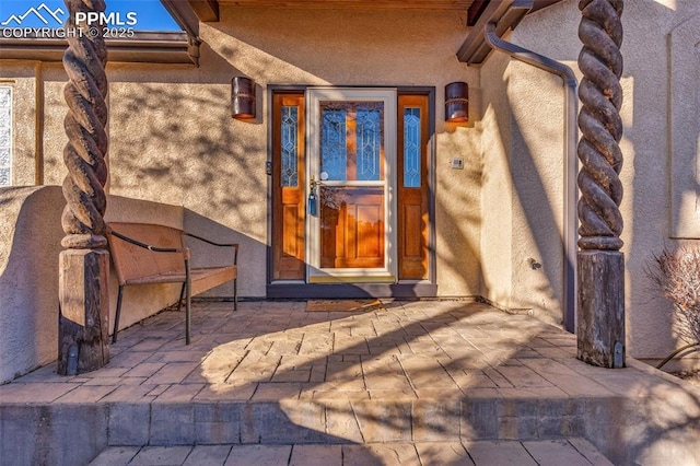 view of exterior entry featuring a patio area and stucco siding