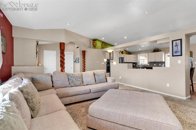 living room featuring carpet, vaulted ceiling, arched walkways, and baseboards