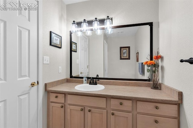 bathroom with a textured wall and vanity