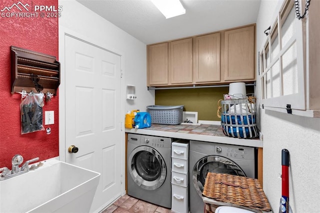 washroom with cabinet space, separate washer and dryer, and a sink