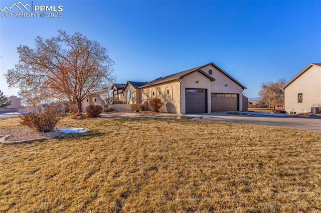 view of front facade with a garage, concrete driveway, a front lawn, and stucco siding