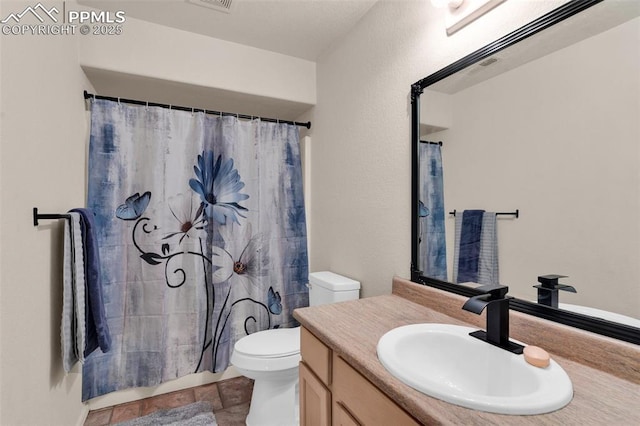 bathroom featuring a shower with curtain, stone finish floor, vanity, and toilet