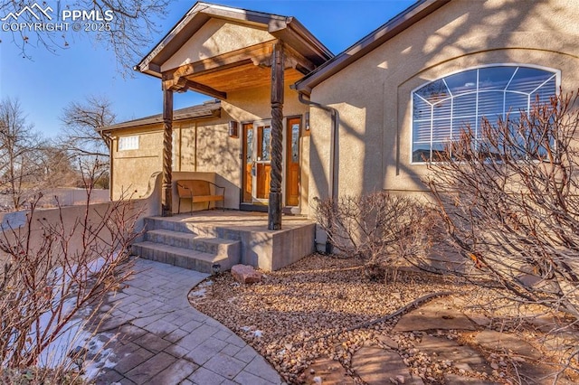 entrance to property featuring a patio and stucco siding