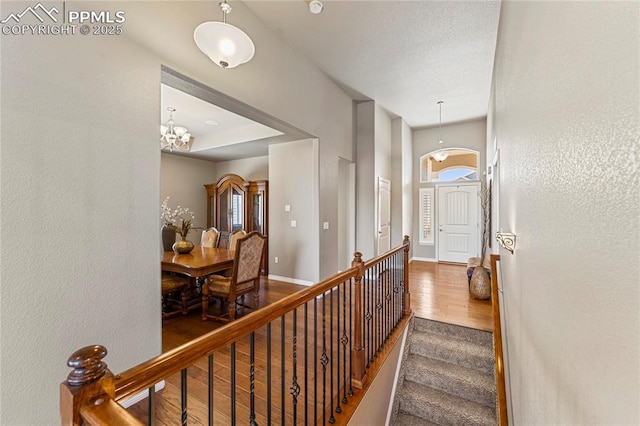 stairs with an inviting chandelier, wood finished floors, and baseboards