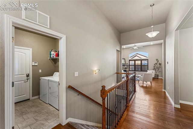 interior space featuring baseboards, visible vents, washer and clothes dryer, an upstairs landing, and light wood-style floors