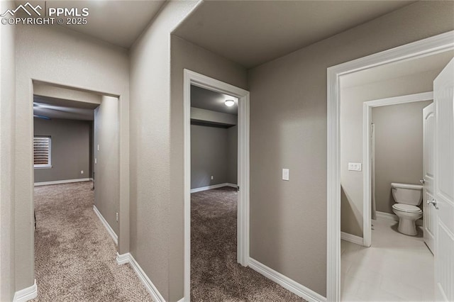 hall featuring carpet and baseboards