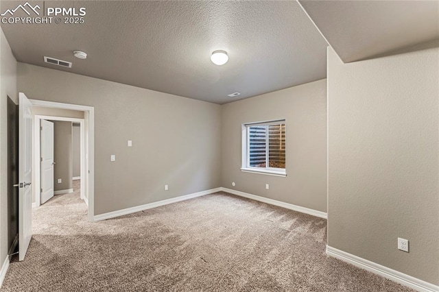 unfurnished room featuring a textured ceiling, carpet flooring, visible vents, and baseboards