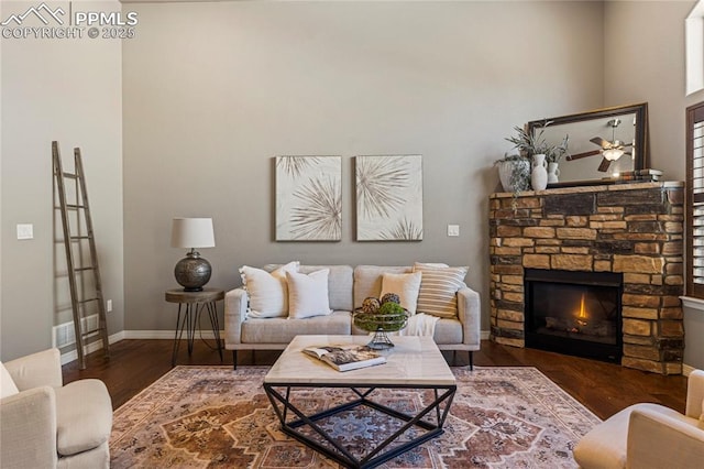 living room featuring a fireplace, baseboards, and wood finished floors