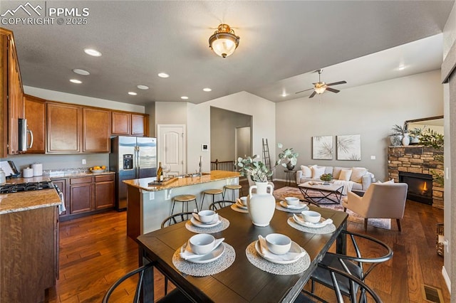 dining area with ceiling fan, a fireplace, dark wood-type flooring, and recessed lighting