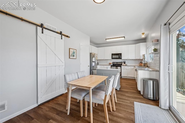 4925 Hawk Meadow Dr, Colorado Springs, CO 80916 - dining space with dark wood-style floors, visible vents, baseboards, and a barn door