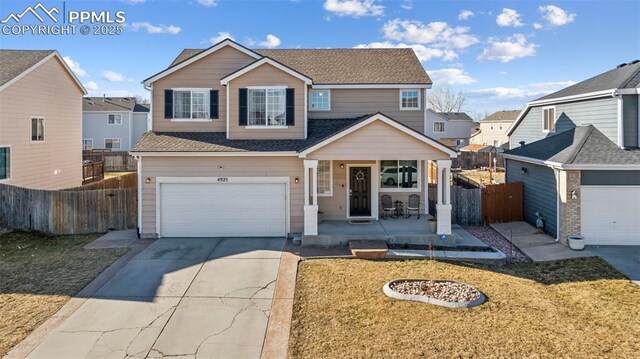 4925 Hawk Meadow Dr, Colorado Springs, CO 80916 - traditional-style house with driveway, roof with shingles, an attached garage, fence, and a porch