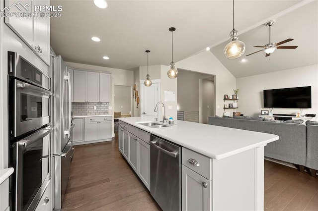 kitchen with stainless steel appliances, dark wood-style flooring, a sink, light countertops, and tasteful backsplash