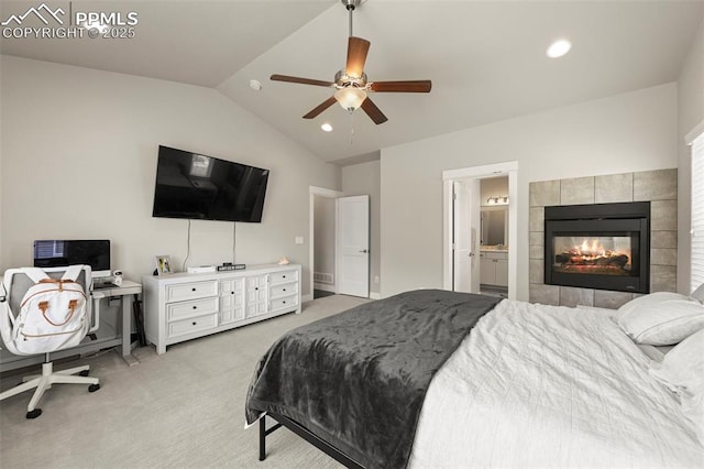 bedroom featuring ensuite bathroom, recessed lighting, light colored carpet, vaulted ceiling, and a tiled fireplace