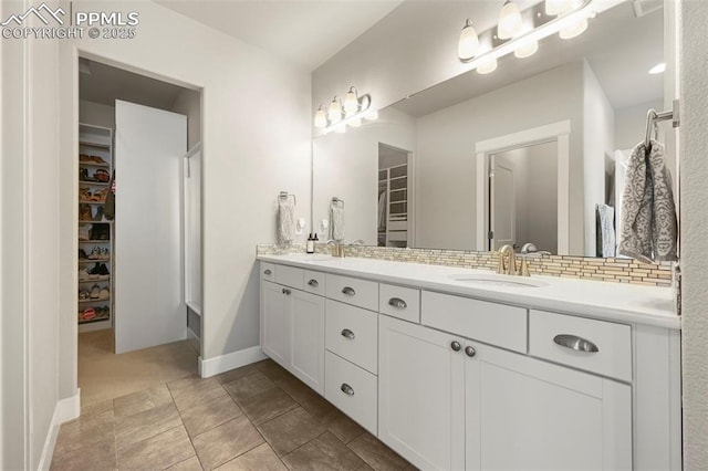 full bath with double vanity, a spacious closet, backsplash, and a sink