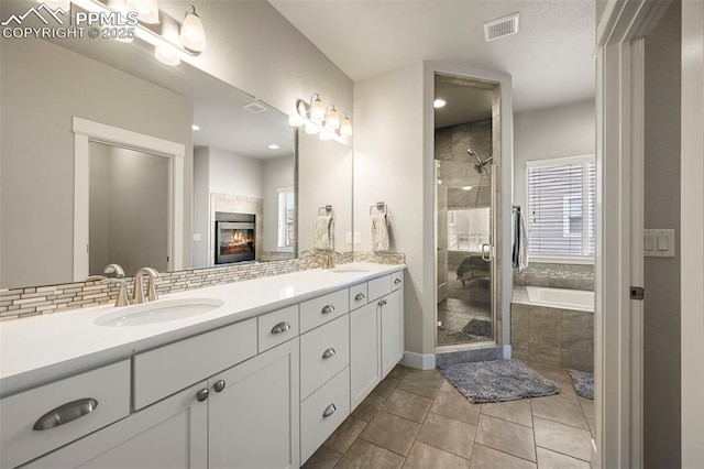 bathroom with a shower stall, visible vents, decorative backsplash, and a sink