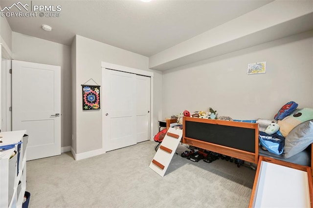 bedroom featuring light carpet, a closet, and baseboards