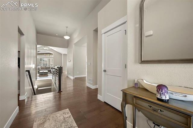 corridor featuring visible vents, dark wood-type flooring, an upstairs landing, and baseboards