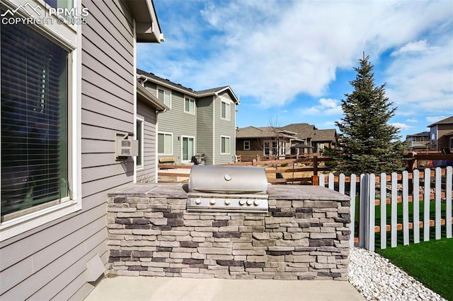 view of patio / terrace featuring exterior kitchen, a grill, a residential view, and fence