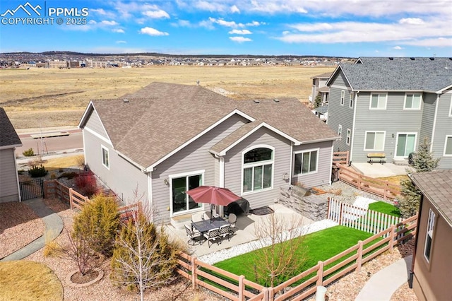 back of house with a patio, a yard, roof with shingles, and a fenced backyard