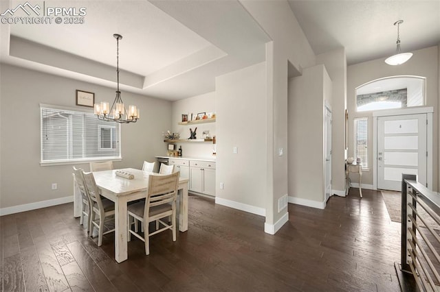 dining space featuring a raised ceiling, dark wood finished floors, and baseboards