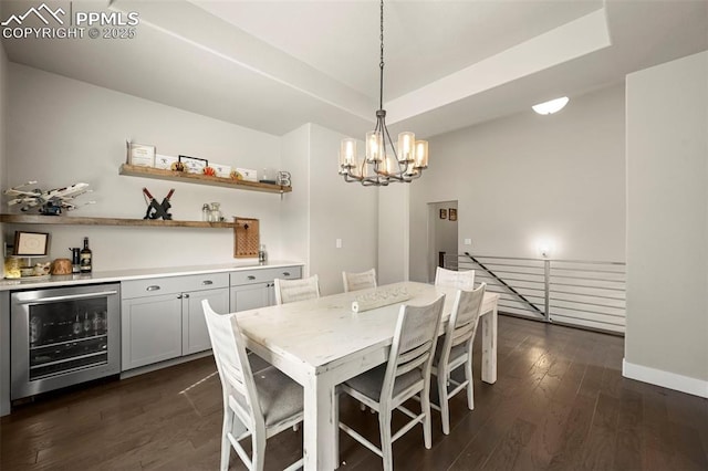 dining space with beverage cooler, a tray ceiling, dark wood finished floors, and baseboards