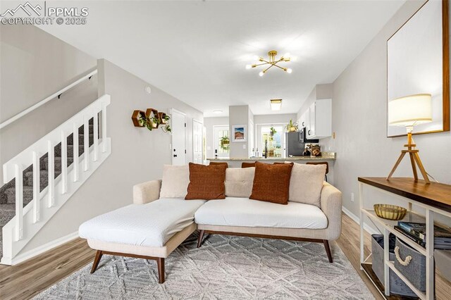 1908 Giltshire Dr, Colorado Springs, CO 80905 - living area with light wood-style flooring, an inviting chandelier, baseboards, and stairs
