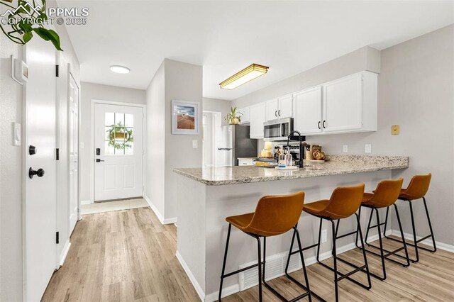 1908 Giltshire Dr, Colorado Springs, CO 80905 - kitchen with baseboards, light wood-type flooring, a kitchen breakfast bar, a peninsula, and stainless steel appliances