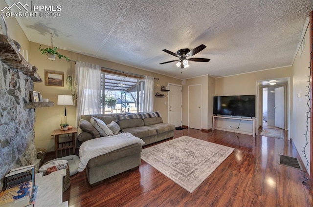 living room featuring a textured ceiling, wood finished floors, visible vents, and a ceiling fan