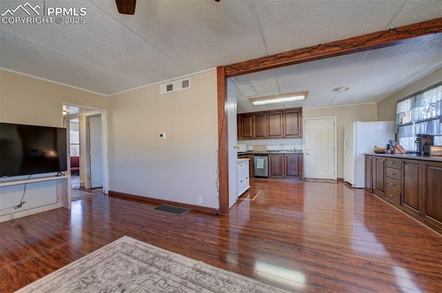 unfurnished living room with a textured ceiling, dark wood-type flooring, a sink, visible vents, and baseboards