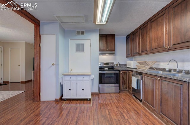 kitchen featuring under cabinet range hood, dark wood-style floors, appliances with stainless steel finishes, and a sink