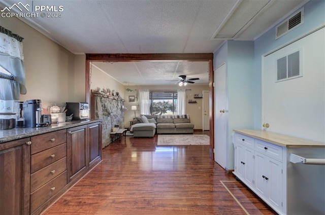 kitchen with a textured ceiling, ceiling fan, visible vents, white cabinets, and dark wood finished floors