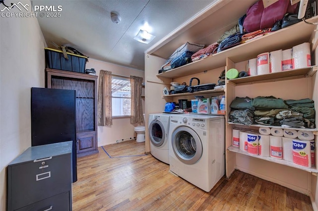 clothes washing area featuring laundry area, light wood finished floors, and washing machine and clothes dryer