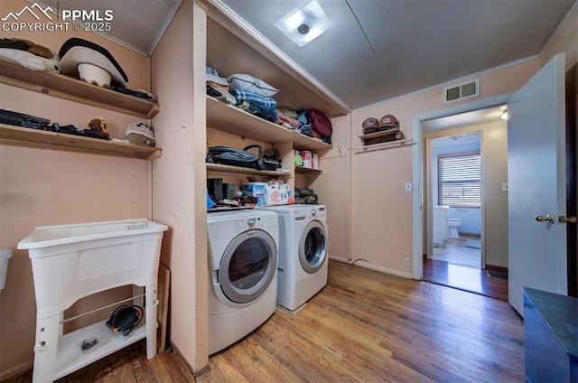 washroom featuring light wood-type flooring, visible vents, and washer and clothes dryer