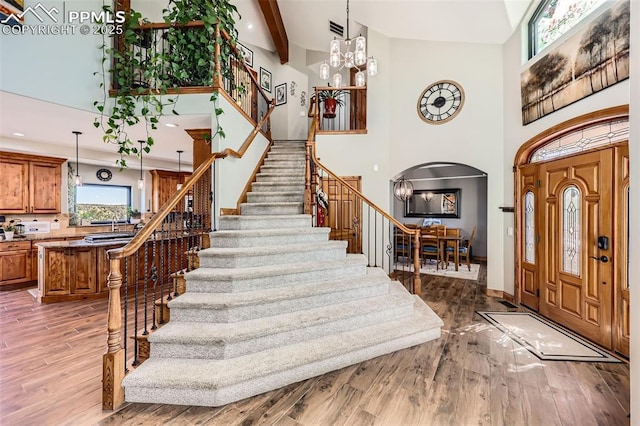 foyer featuring stairway, arched walkways, wood finished floors, and an inviting chandelier