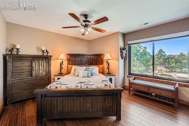 bedroom with a ceiling fan, visible vents, dark wood finished floors, and baseboards