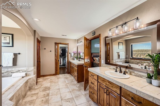 full bath with a garden tub, a spacious closet, visible vents, and vanity