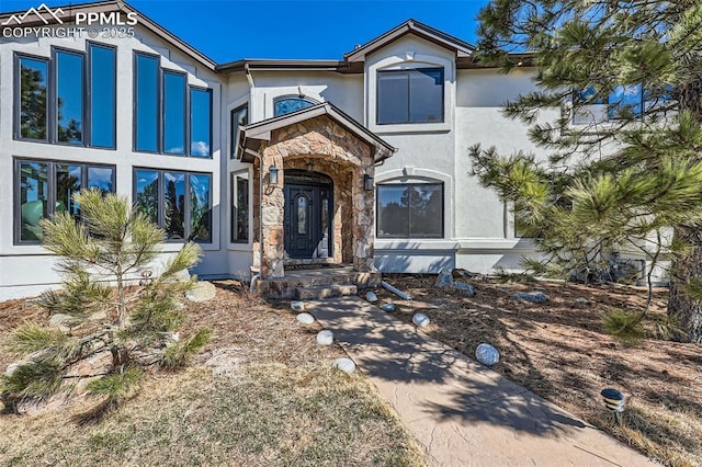 view of front of house featuring stone siding and stucco siding