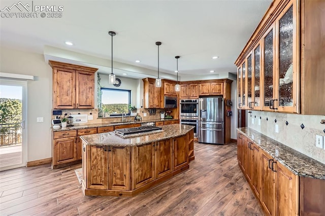 kitchen featuring a kitchen island, appliances with stainless steel finishes, brown cabinetry, and a sink