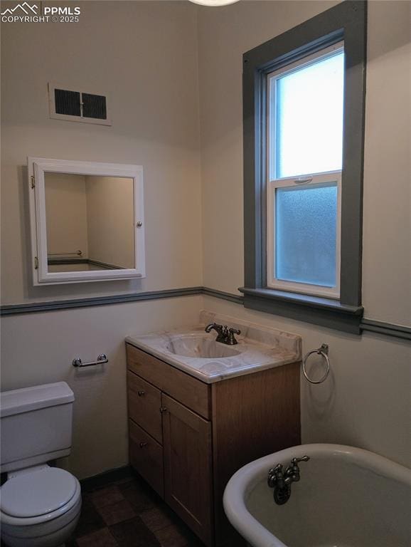 full bathroom featuring toilet, a soaking tub, visible vents, and vanity