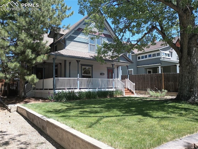 victorian home with covered porch, fence, and a front lawn