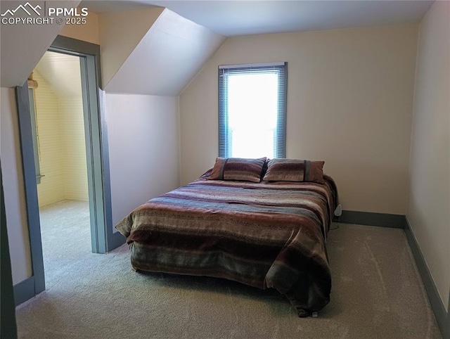 bedroom with carpet floors, lofted ceiling, and baseboards