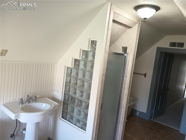 bathroom featuring vaulted ceiling, a sink, a shower stall, and visible vents