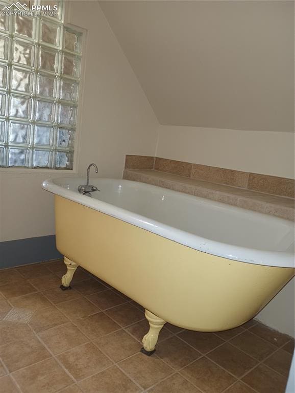 full bathroom with vaulted ceiling, tile patterned flooring, and a freestanding tub