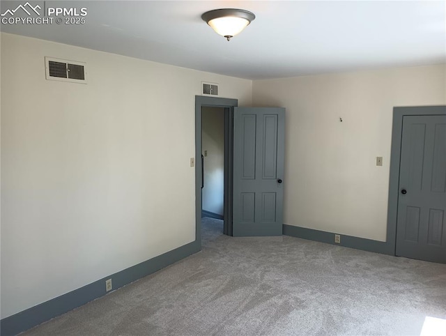 carpeted empty room featuring baseboards and visible vents