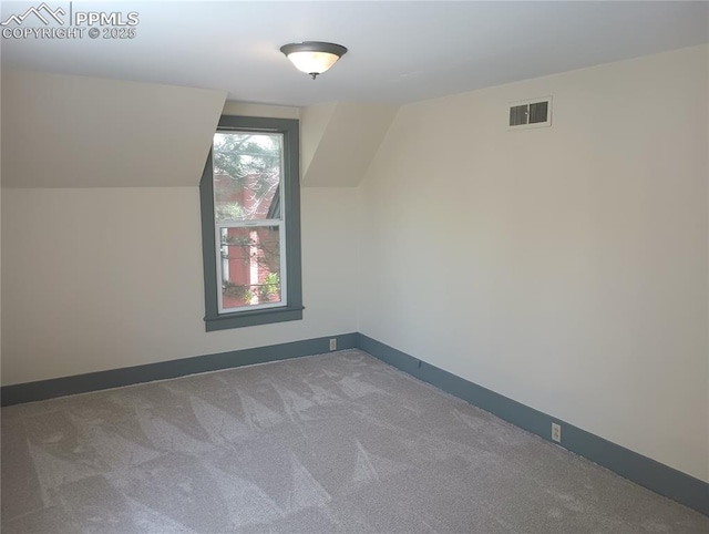 bonus room featuring baseboards, visible vents, vaulted ceiling, and carpet flooring