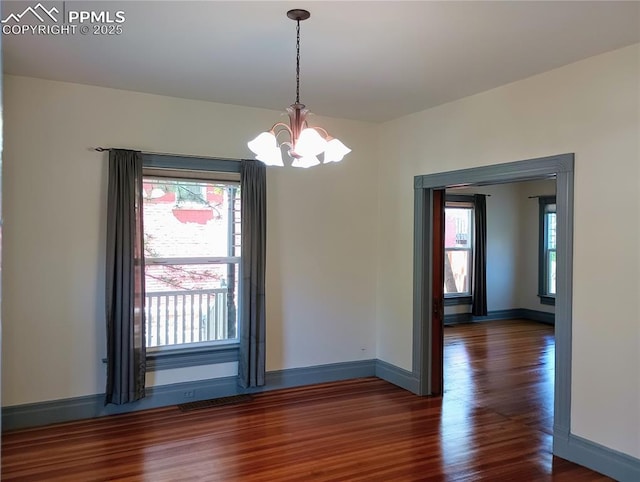 unfurnished dining area with an inviting chandelier, baseboards, and wood finished floors