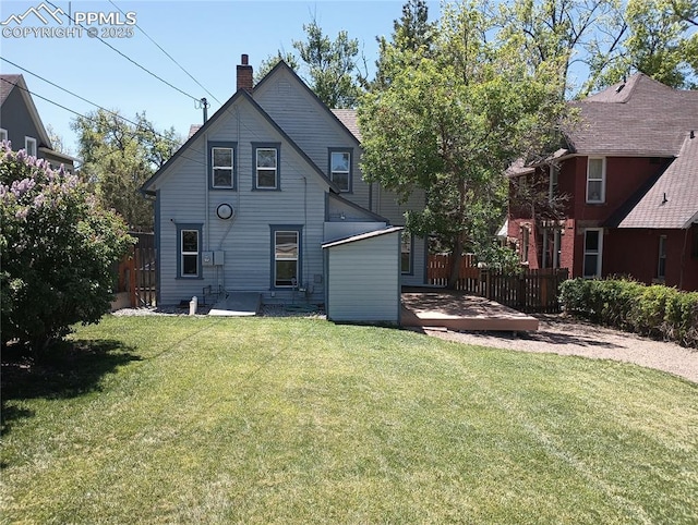 back of property with a chimney, fence, and a yard