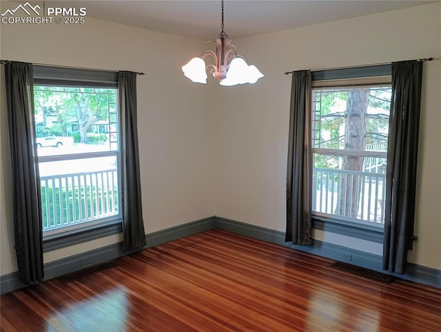 empty room featuring plenty of natural light, dark wood finished floors, visible vents, and baseboards