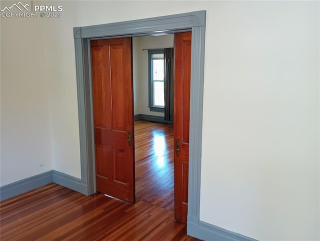 hall with baseboards and wood finished floors